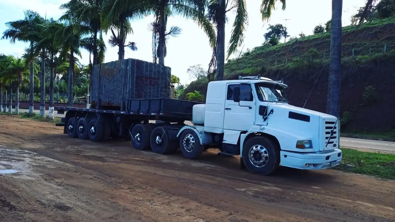 Cavalo mecânico com bloco de rocha na carreta, em estrada de terra